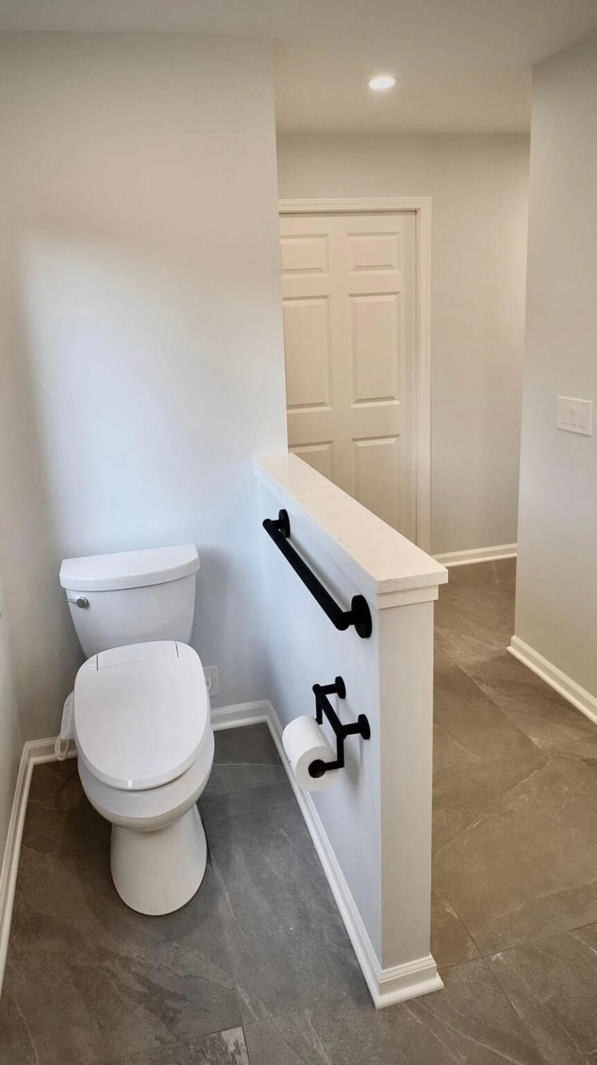 Comfort-height toilet with a grab bar and a reachable paper holder on a half-wall, with clear floor space alongside for a transfer, Mesa, AZ