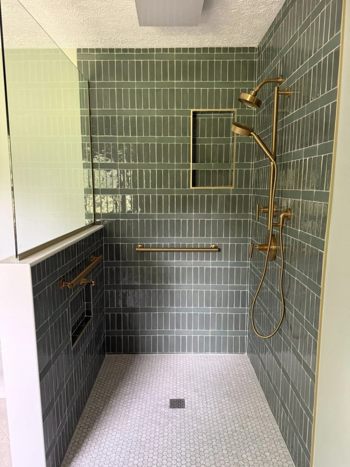 Roll-in shower finished in green tile with brass grab bars, dual shower heads and a slip-resistant hex mosaic floor, Mesa, AZ