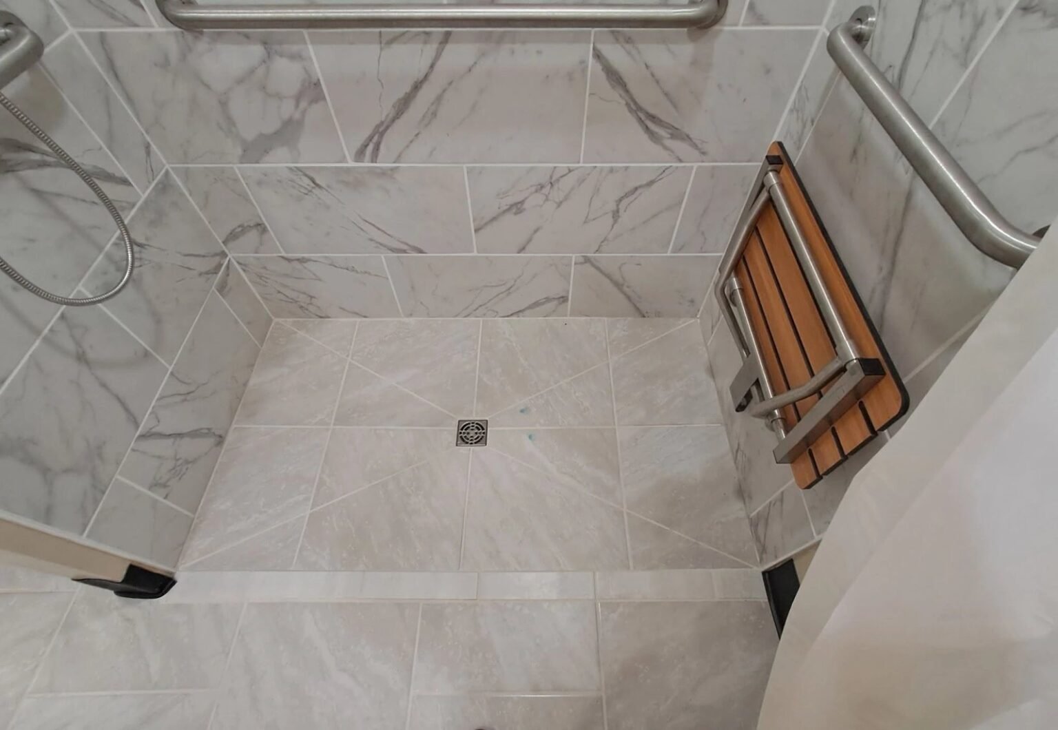 Curbless roll-in shower with a teak fold-down seat, grab bars and a hand-held shower, accessible bathroom remodeling in Mesa, AZ