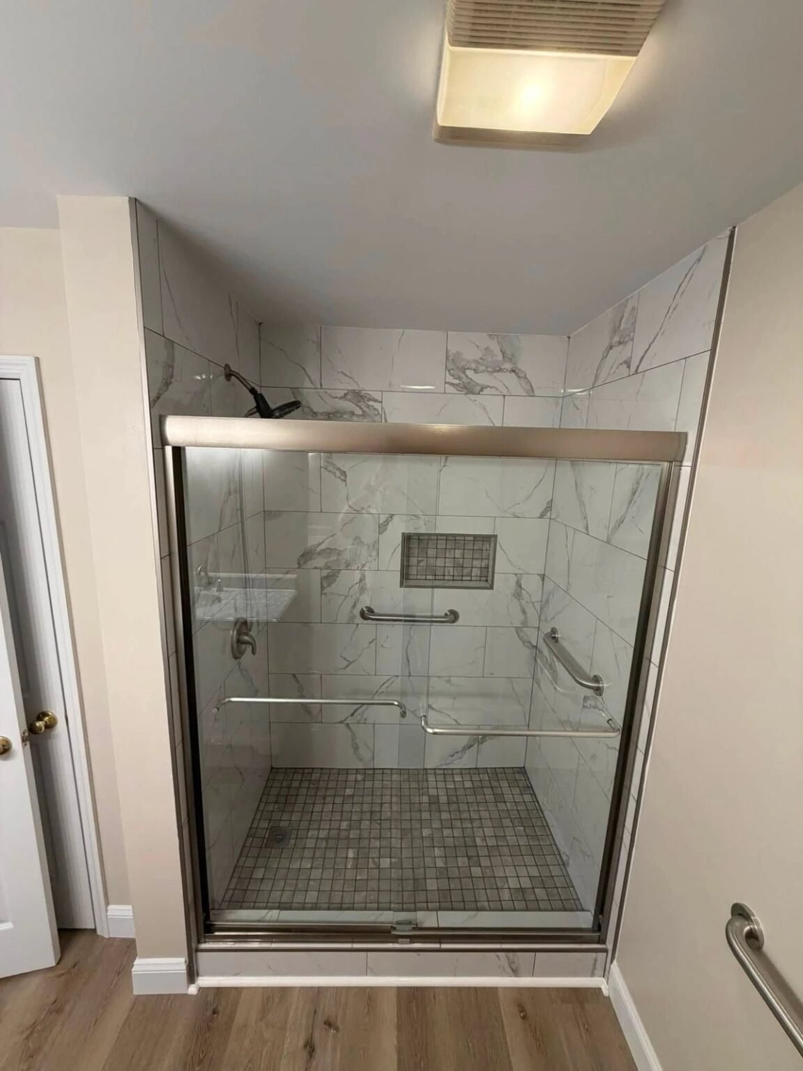 Transfer shower with grab bars on two walls, a recessed niche and a sliding glass door, accessible bathroom remodel in Mesa, AZ